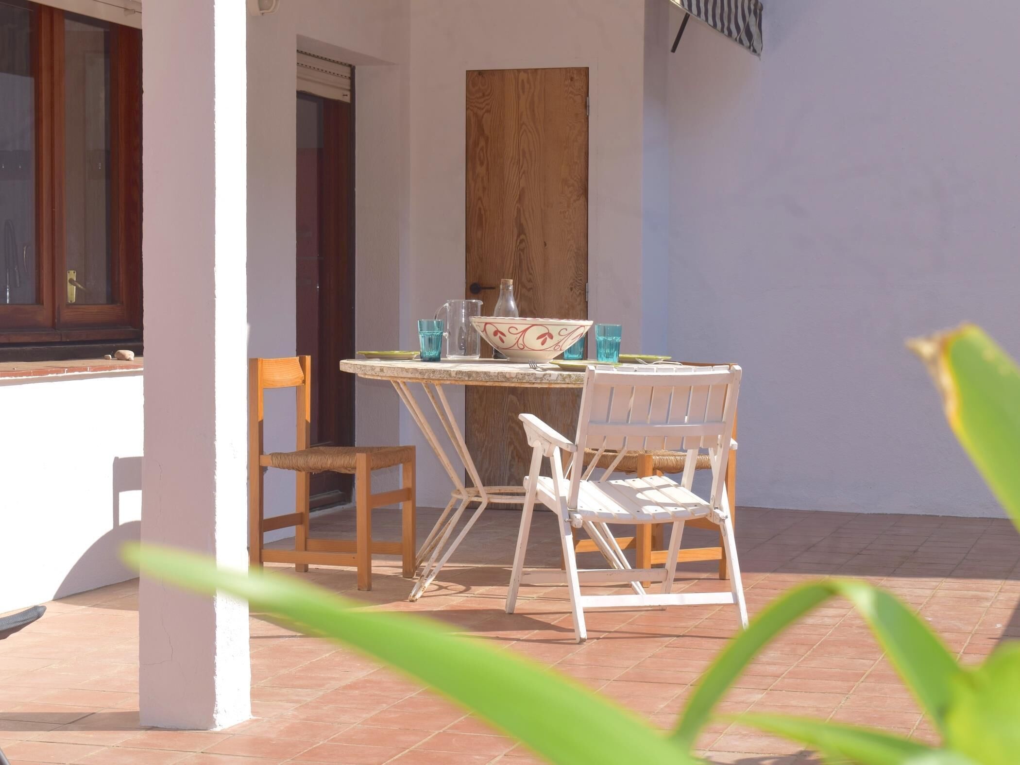 Un patio con una mesa, sillas, una puerta de madera y una ventana.