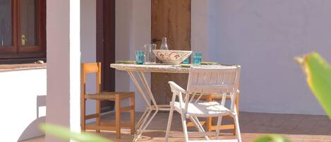Un patio con una mesa, sillas, una puerta de madera y una ventana.