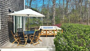 Une terrasse en bois avec des meubles d’extérieur, une table et un parasol.