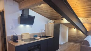 Eine moderne Küche mit schwarzen Geräten, einer Holzbalkendecke und einem eingebauten Ofen.