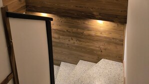 Eine Holzvertäfelung mit zwei gerahmten Kunstwerken und einem kleinen Regal.