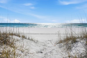 Ein Strand mit freiem Blick auf den Ozean und einem sandigen Pfad zum Wasser.
