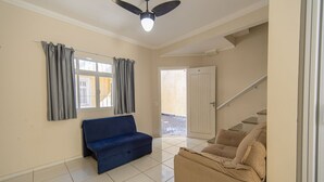 A living room with a blue sofa, beige sofa, and a ceiling fan. - Sua Casa na Enseada Perto da Praia e de Tudo (Guarujá)