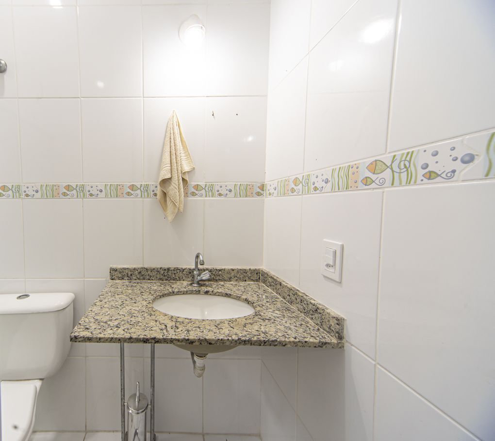 Een badkamer met een wastafel met een granieten blad, een toilet en een handdoek aan de muur.