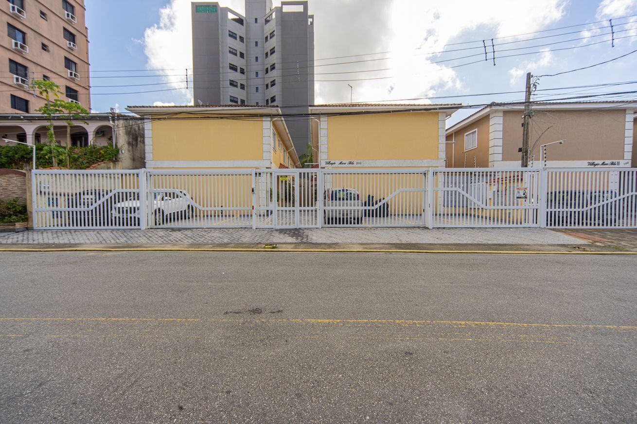 A gated parking area with a yellow building in the background.