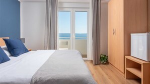 A bedroom with a bed, a wardrobe, a television, and a view of the sea through a sliding door. - Beachfront Villa Victoris – Private Sunbeds (Podstrana)