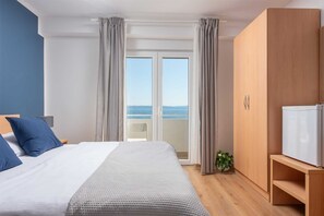 A bedroom with a bed, a wardrobe, a television, and a view of the sea through a sliding door. - Beachfront Villa Victoris – Private Sunbeds (Podstrana)