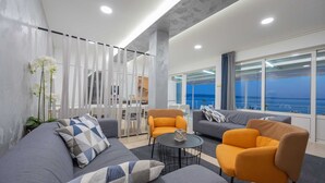 A modern living room with a sofa, armchairs, a coffee table, and a view of the sea. - Beachfront Villa Victoris – Private Sunbeds (Podstrana)