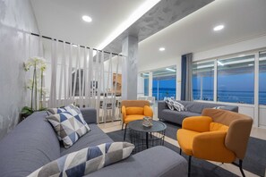 A modern living room with a sofa, armchairs, a coffee table, and a view of the sea. - Beachfront Villa Victoris – Private Sunbeds (Podstrana)