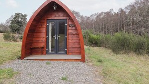Una pequeña cabaña de madera con techo inclinado y una puerta con paneles de vidrio.