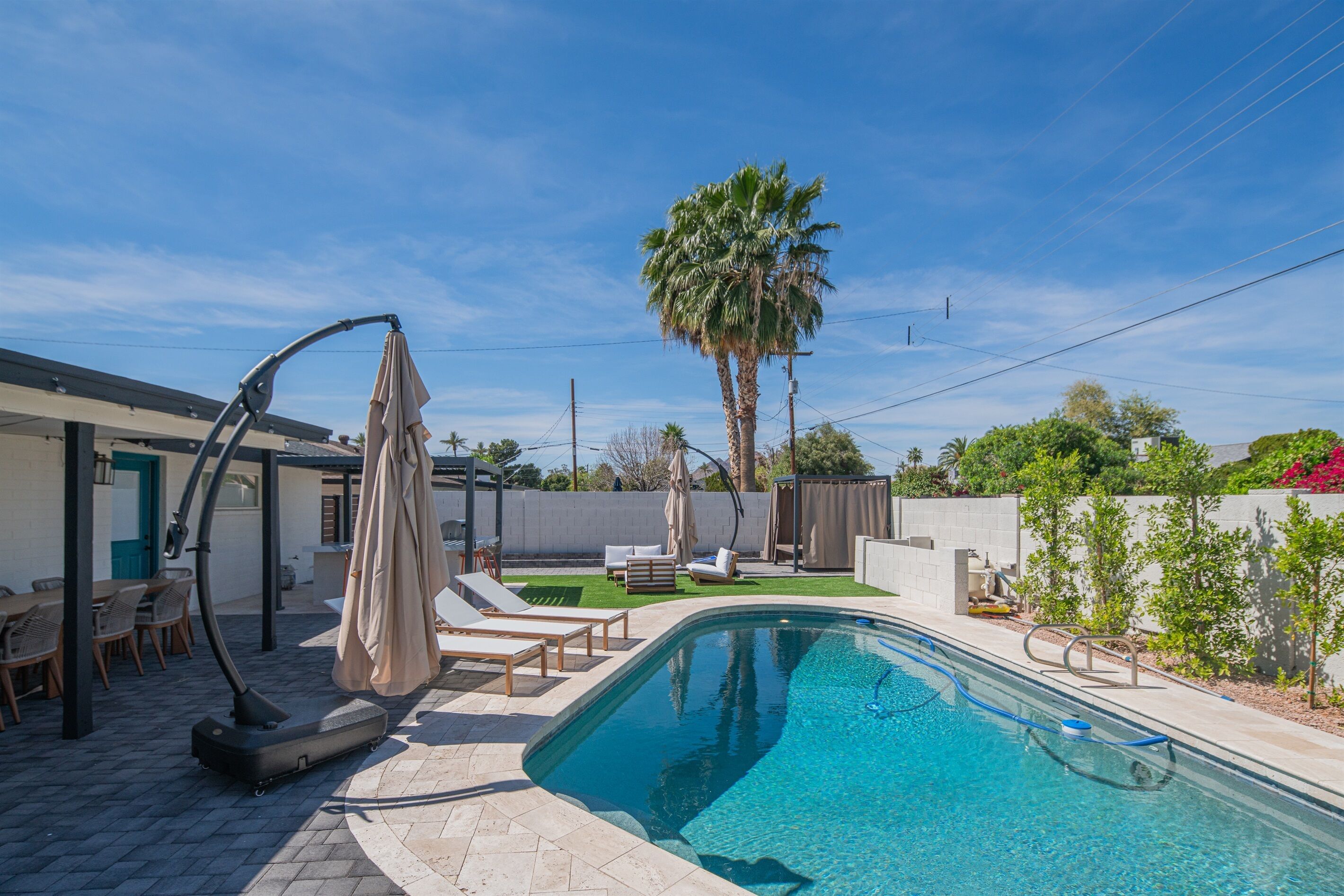 Une piscine dotée de chaises longues et d’un ventilateur de plafond, entourée d’un patio agrémenté d’un palmier.