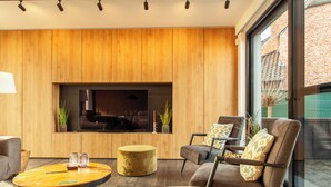 A modern living room with a large TV, wooden panel walls, and comfortable seating. - 8P 4B Luxury Villa Close to Maastricht (Lanaken)