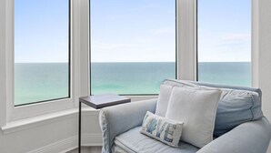 A room with a view of the ocean through large windows, a light blue sofa, and a small table. - Emerald Beach 1736 (Panama City Beach)