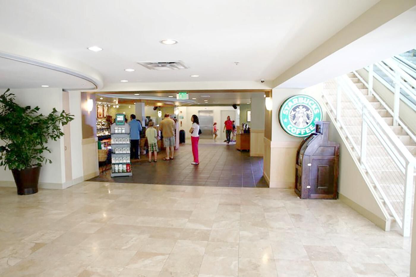 Tilava aula, jossa on Starbucks-kahvila, vastaanottotiski ja portaikko.
