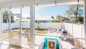 Eine Terrasse mit einem grünen Sofa, einem Grill und einem weißen Zaun.