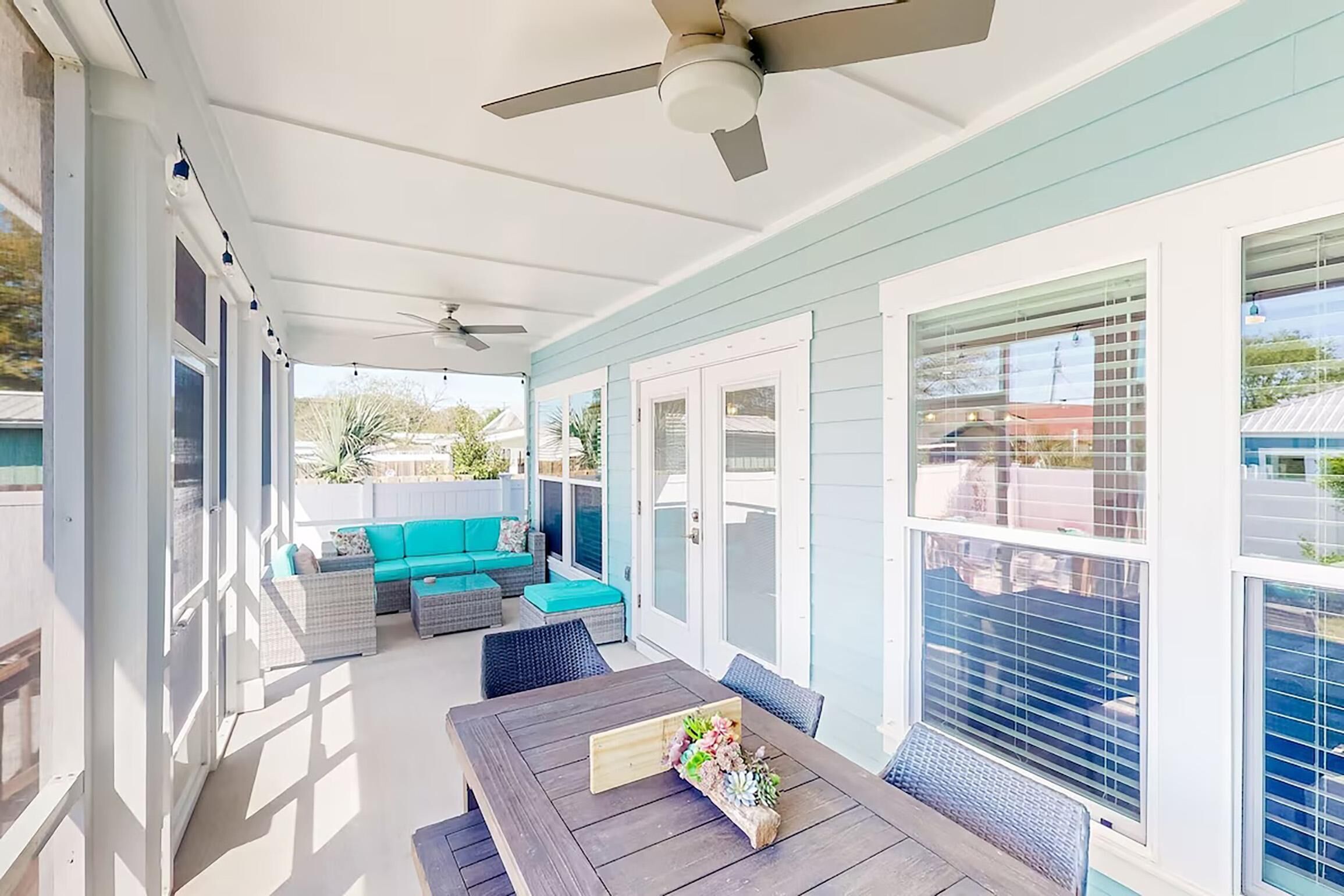 A covered patio with a dining table, outdoor seating, and a ceiling fan.