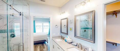 Un baño moderno con cabina de ducha de vidrio, tocador doble y un espejo grande.