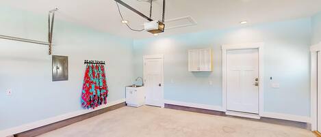 A spacious room with a light blue wall, a ceiling-mounted projector, a white cabinet, and a colorful beach towel on the wall.