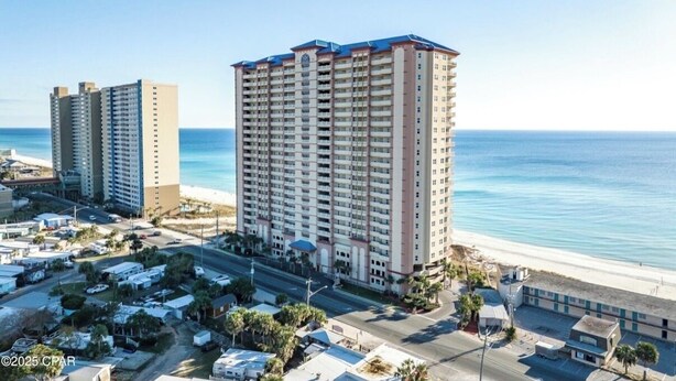 Ein Hochhaus-Hotel mit mehreren Etagen, Blick auf den Strand und einem Parkplatz im Vordergrund.