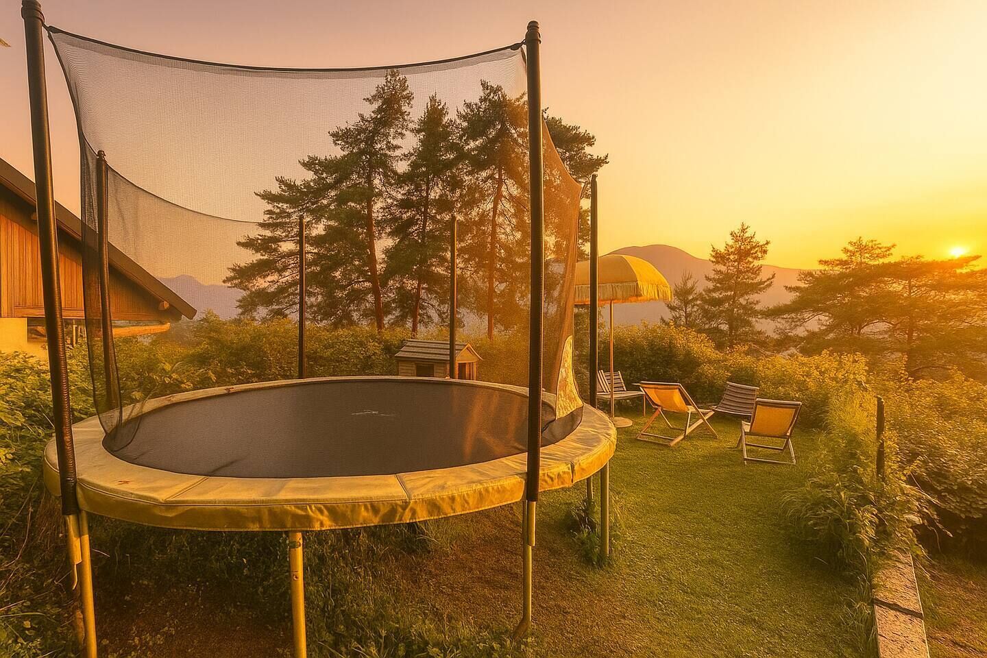 A trampoline in a backyard with a net canopy, surrounded by trees and a view of a mountain at sunset.