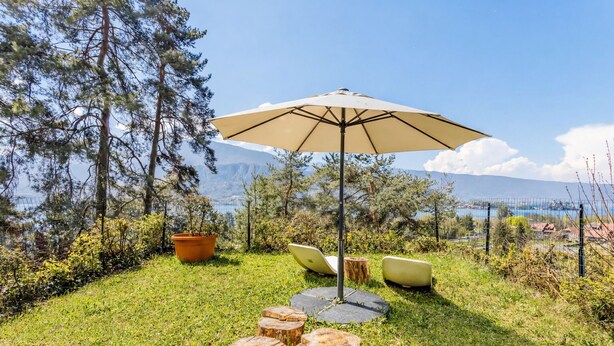 A grassy outdoor area with a large umbrella, wooden stools, and a potted plant. - Panoramic terrace apartment 200 meters from the lake 2 terraces (Talloires-Montmin)