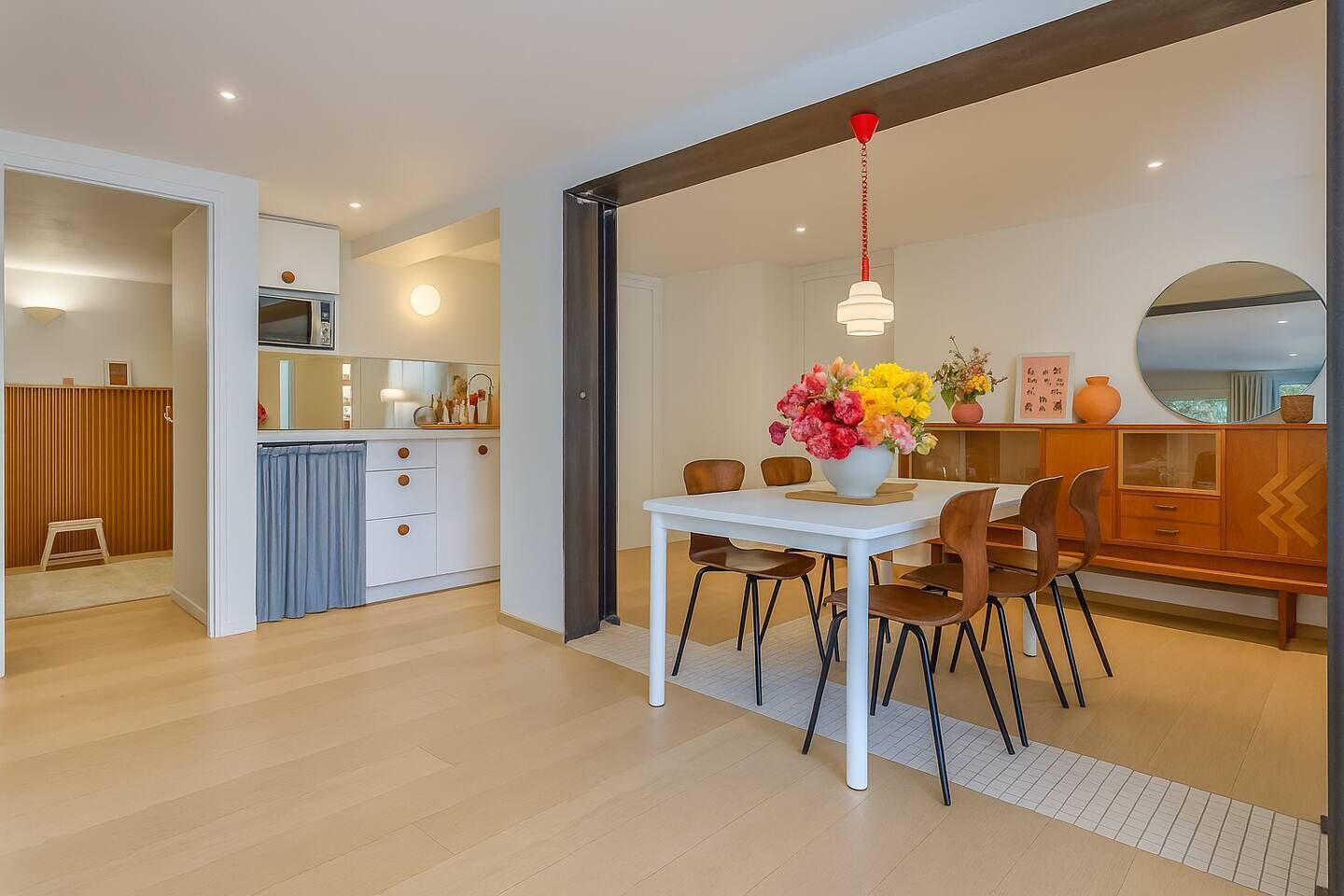Cozinha moderna com micro-ondas, armários e uma área de jantar com mesa e cadeiras brancas.