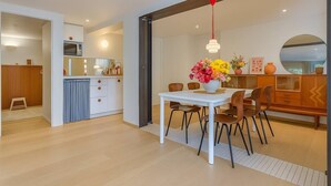 A modern kitchen with a microwave, cabinets, and a dining area with a white table and chairs. - Panoramic terrace apartment 200 meters from the lake 2 terraces (Talloires-Montmin)