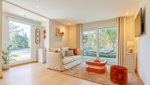 A modern living room with a sofa, a coffee table, and a TV mounted on the wall. - Panoramic terrace apartment 200 meters from the lake 2 terraces (Talloires-Montmin)