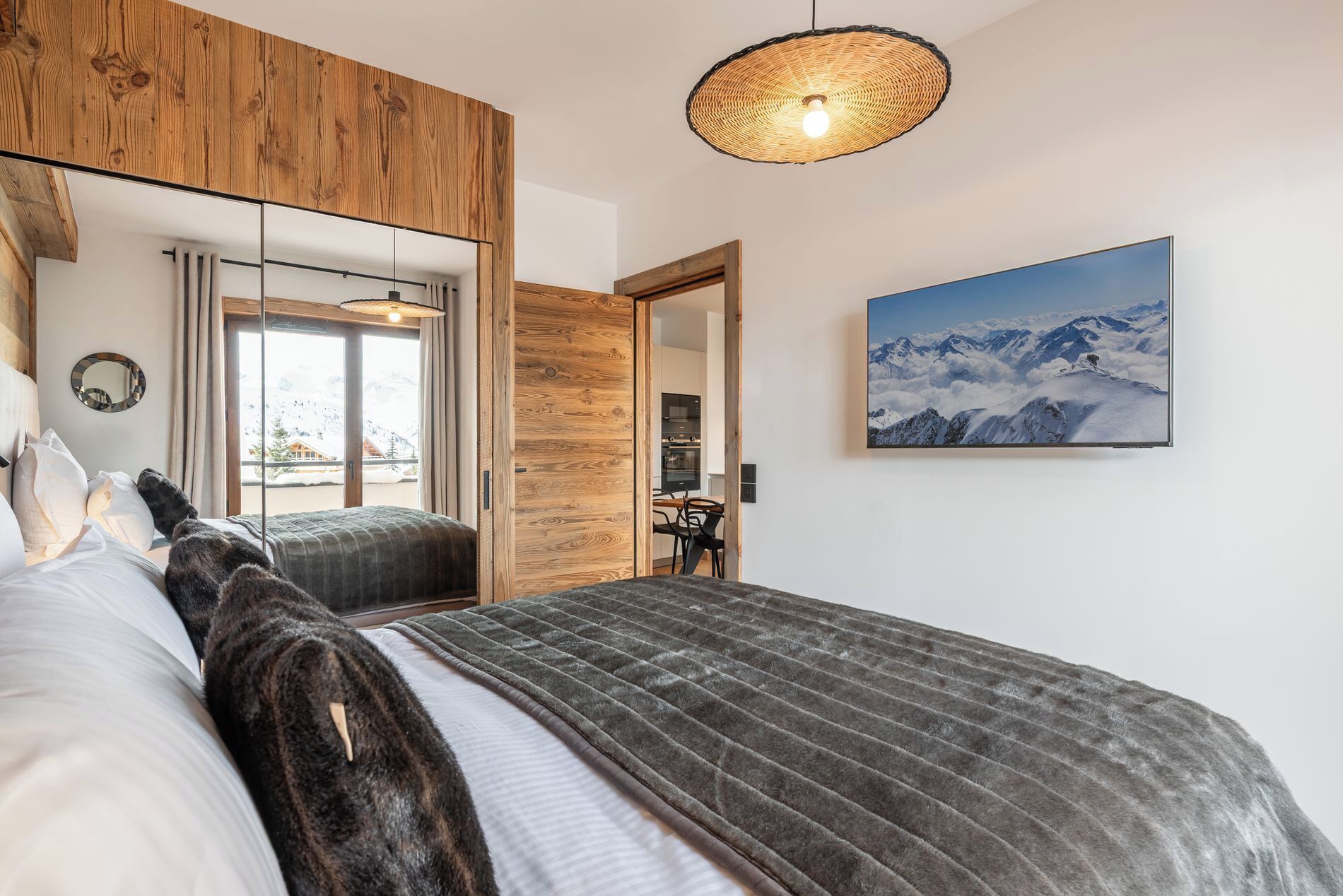 Une chambre dotée d’un grand lit, d’une armoire en bois, d’un coin repas et offrant une vue sur la montagne.
