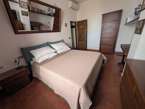 Ein Schlafzimmer mit einem Bett, einem Nachttisch, einer Kommode, einem Spiegel, einem Kleiderschrank und einem Regal mit Büchern und einer Trophäe.