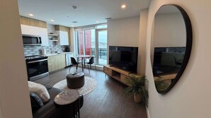 A modern apartment with a kitchen, dining area, living room, and a balcony with a city view. - Waterfront 1 BR with 6 appliances and huge patio (Halifax)