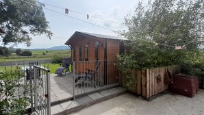 Una casa de madera con balcón, un patio cercado y vistas al campo.