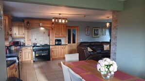 Una cocina con armarios de madera, una estufa y un comedor con mesa y sillas.