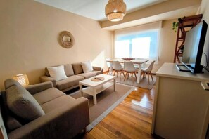 Ein modernes Wohnzimmer mit Sofa, Couchtisch und Essbereich.