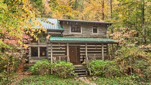 A rustic log cabin with a green metal roof, surrounded by autumn foliage. - 3 Brothers Rustic Sabbatical Creekside Cabin (Walland)
