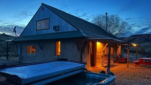 A rustic cabin with a hot tub, wooden deck, and outdoor seating area.