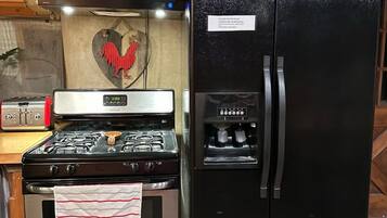 A kitchen with a stainless steel stove, a black refrigerator, and wooden cabinets.