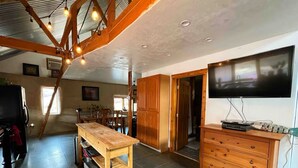 A spacious living area with a wooden dining table, a TV, and a wooden cabinet.