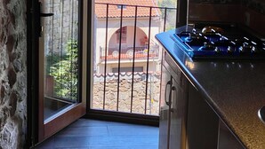 Une cuisine donnant sur un bâtiment à toit rouge et un mur de pierre situé à l’extérieur.