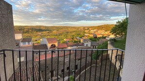 Un balcon donnant sur une ville, des bâtiments en pierre et un ciel nuageux.