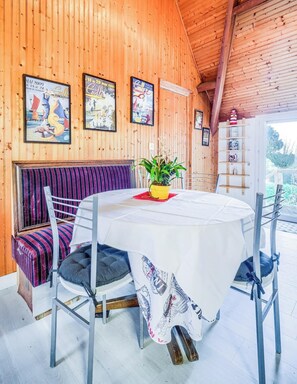 Een houten interieur met een ronde tafel, een gestreept bankje en ingelijste posters aan de muur.