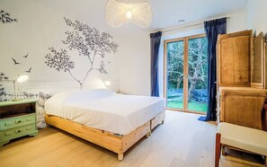 Una camera da letto con un letto di legno, un comodino verde, un armadio in legno e un'ampia finestra con tende.