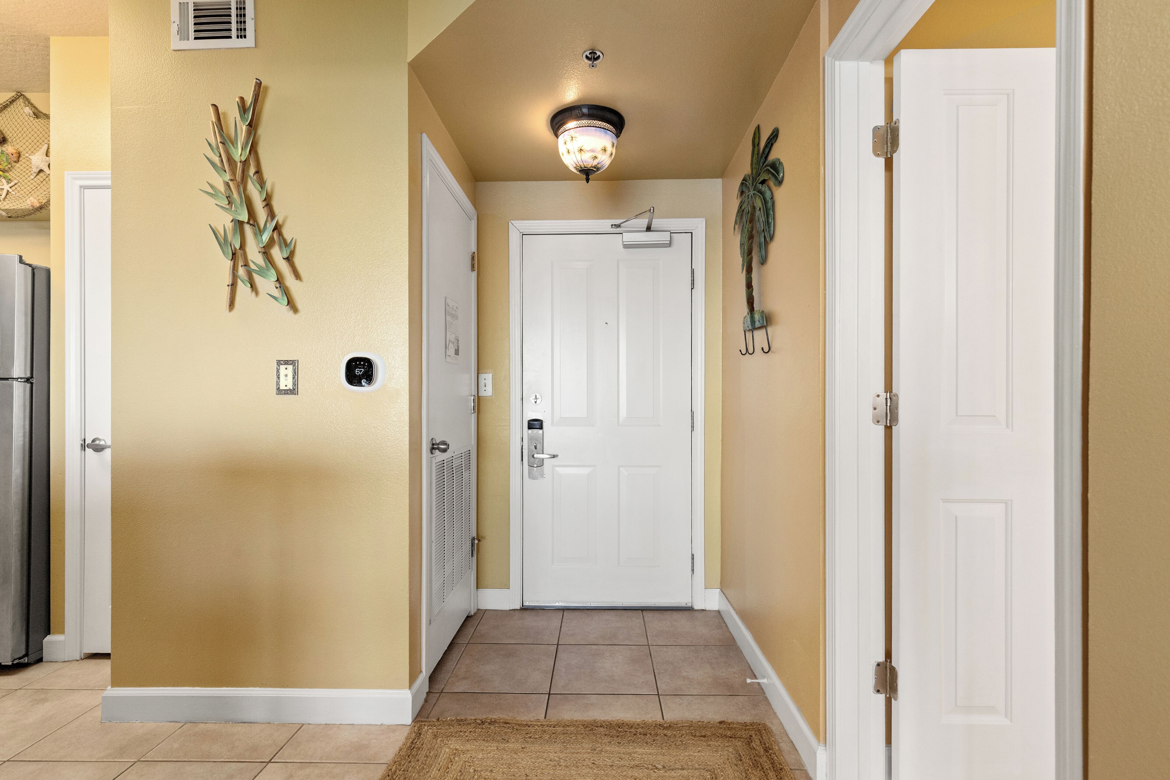 A hallway with beige walls, a white door, and a ceiling light fixture.