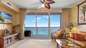 A living room with a large sliding glass door leading to a balcony with a view of the ocean. - Come Visit Sophomore! 2BR 2BA Beachfront Condo! (Panama City Beach)