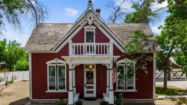 A red house with a white porch and a small front yard.