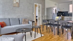 Un salon moderne avec un canapé gris, une table basse et un coin repas comprenant des chaises et une table.