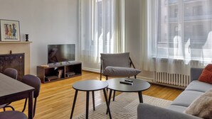 Un salon moderne comprenant un canapé, deux fauteuils, une table basse, un téléviseur posé sur un meuble et une cheminée.