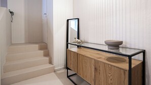 Una escalera que conduce a una plataforma con un armario de madera y un tazón encima.