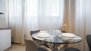 Un comedor con una mesa redonda de vidrio preparada para cuatro personas, rodeada de sillas.