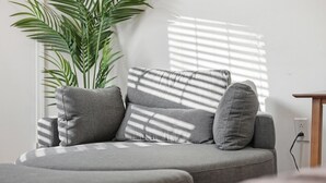 Un canapé gris, avec une grande plante en pot placée à côté.
